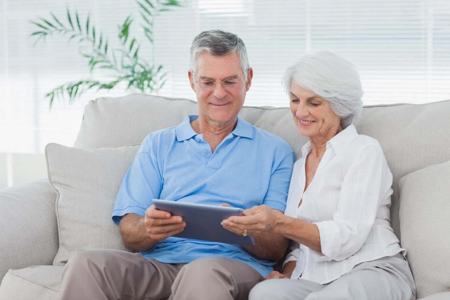 Older couple on a sofa looking over Medicare plan details together on a tablet