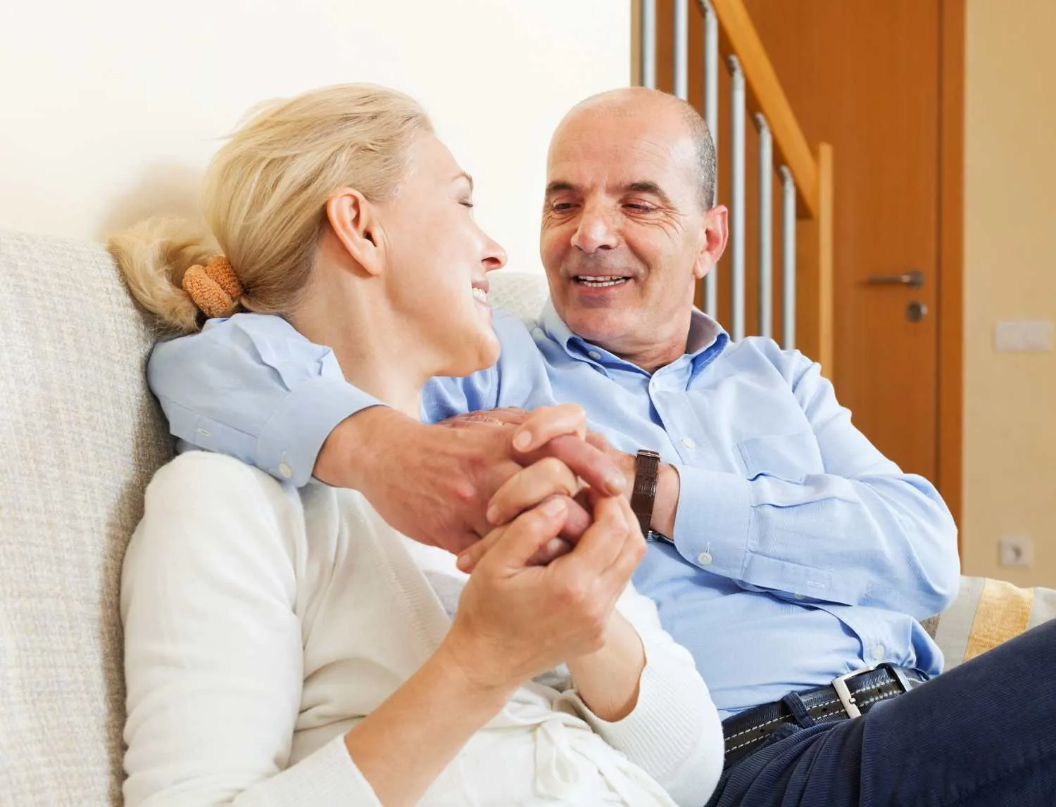 Older couple laughing together on a sofa at home